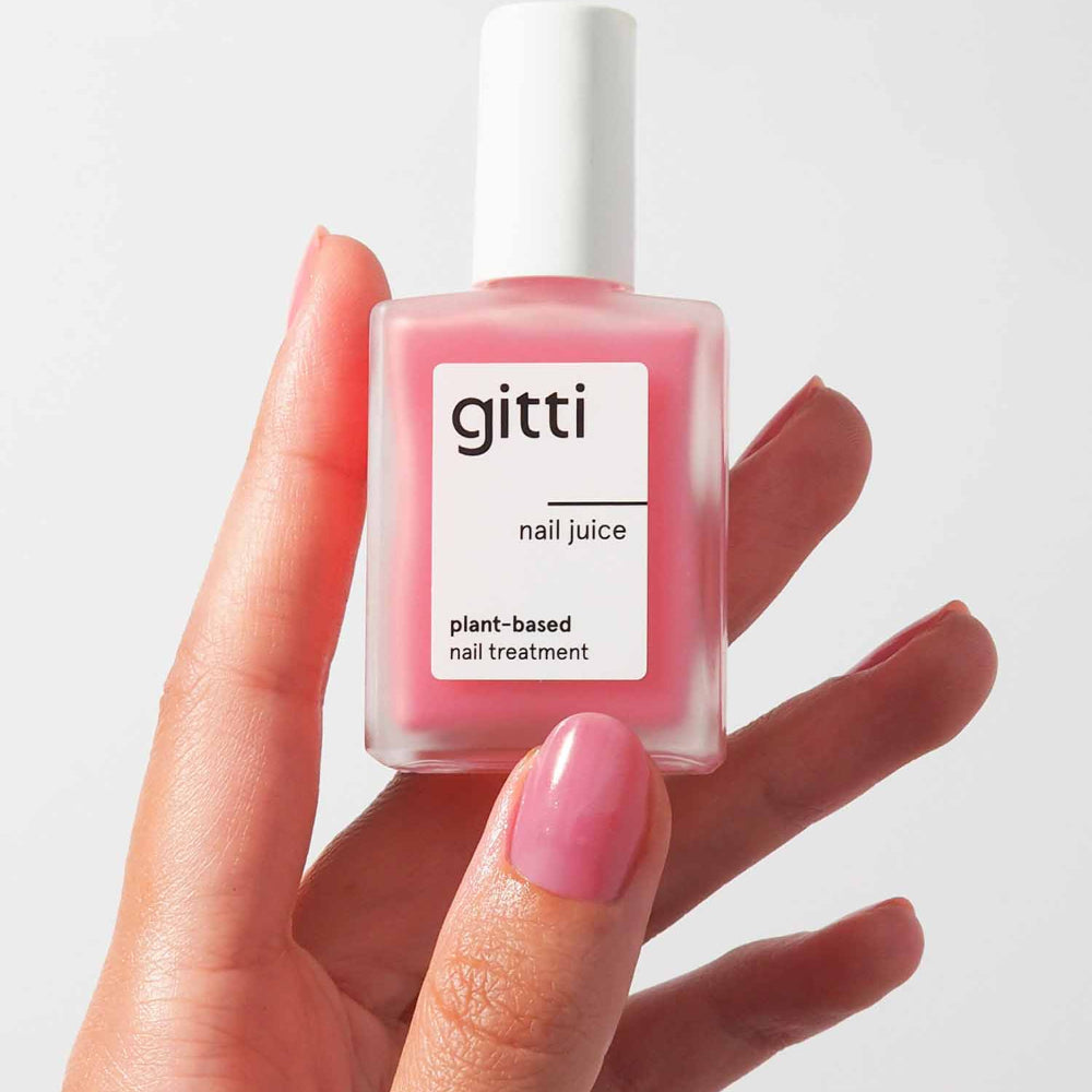 Hand holding a bottle of gitti nail juice with a white background