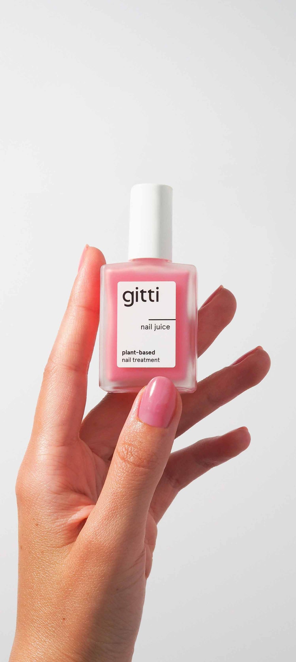 Hand holding a bottle of gitti nail juice with a white background