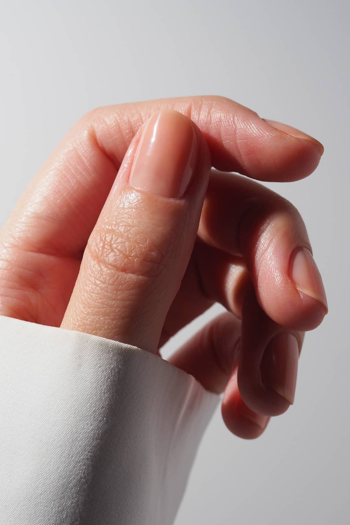 Close-up of a hand with light peach nail polish.
