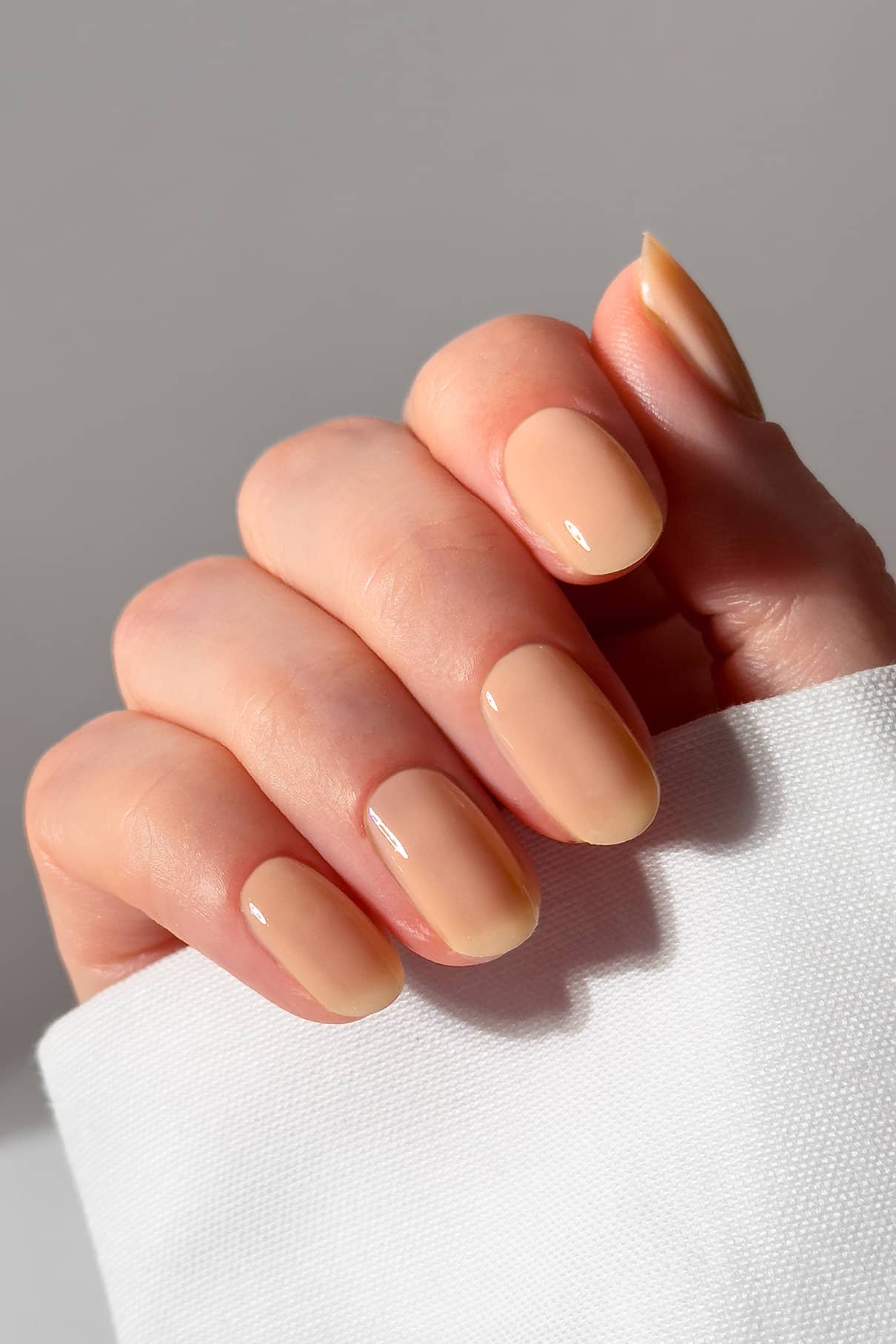 Hand with light peach nail polish. 
