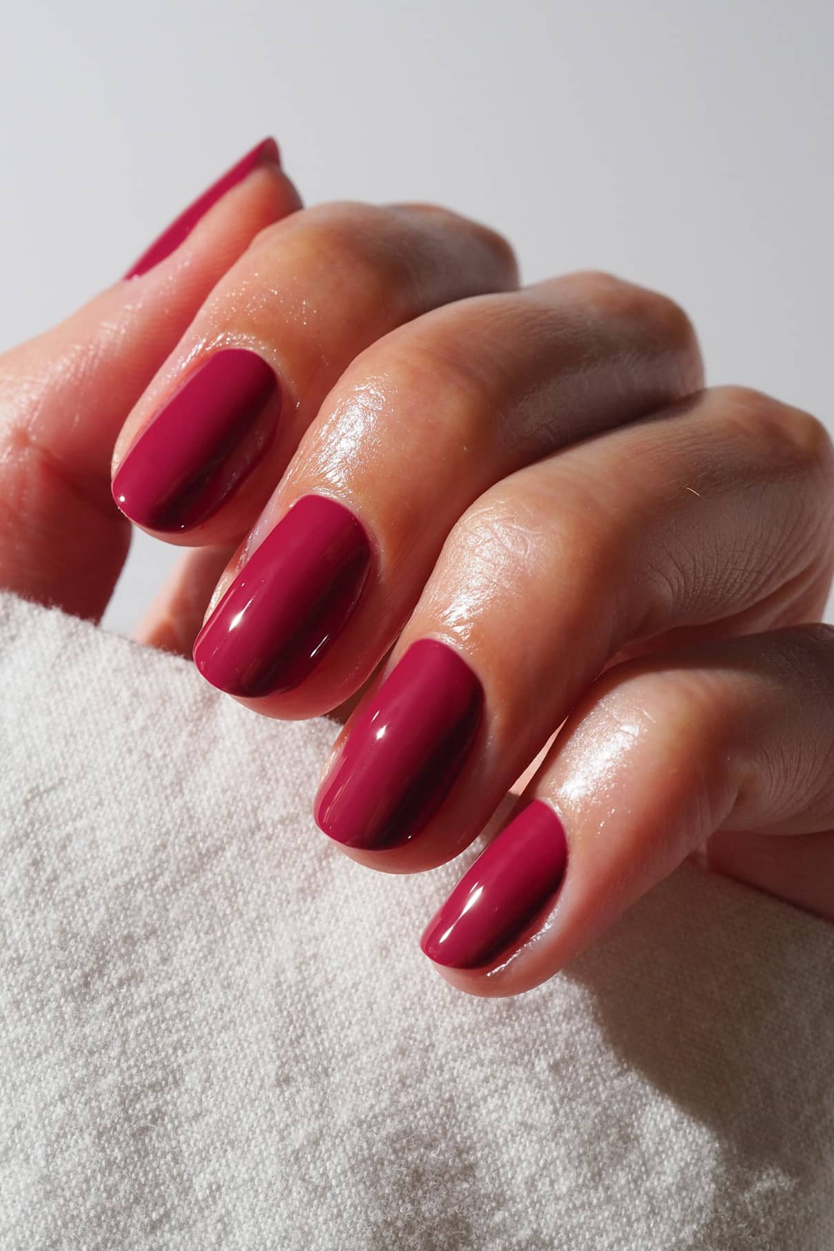 Close-up of a hand with pink nail polish on a white background