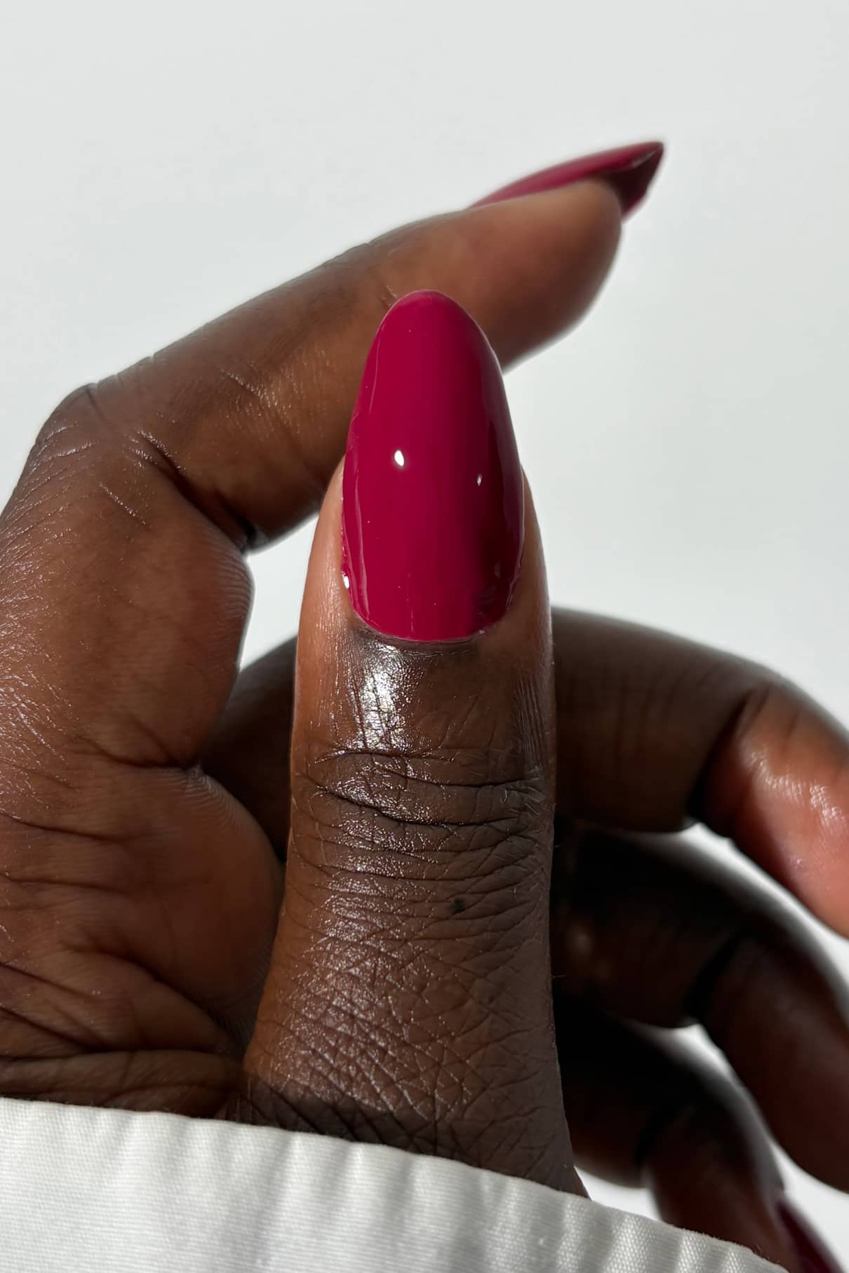 Close-up of a hand with a pink nail on a white background