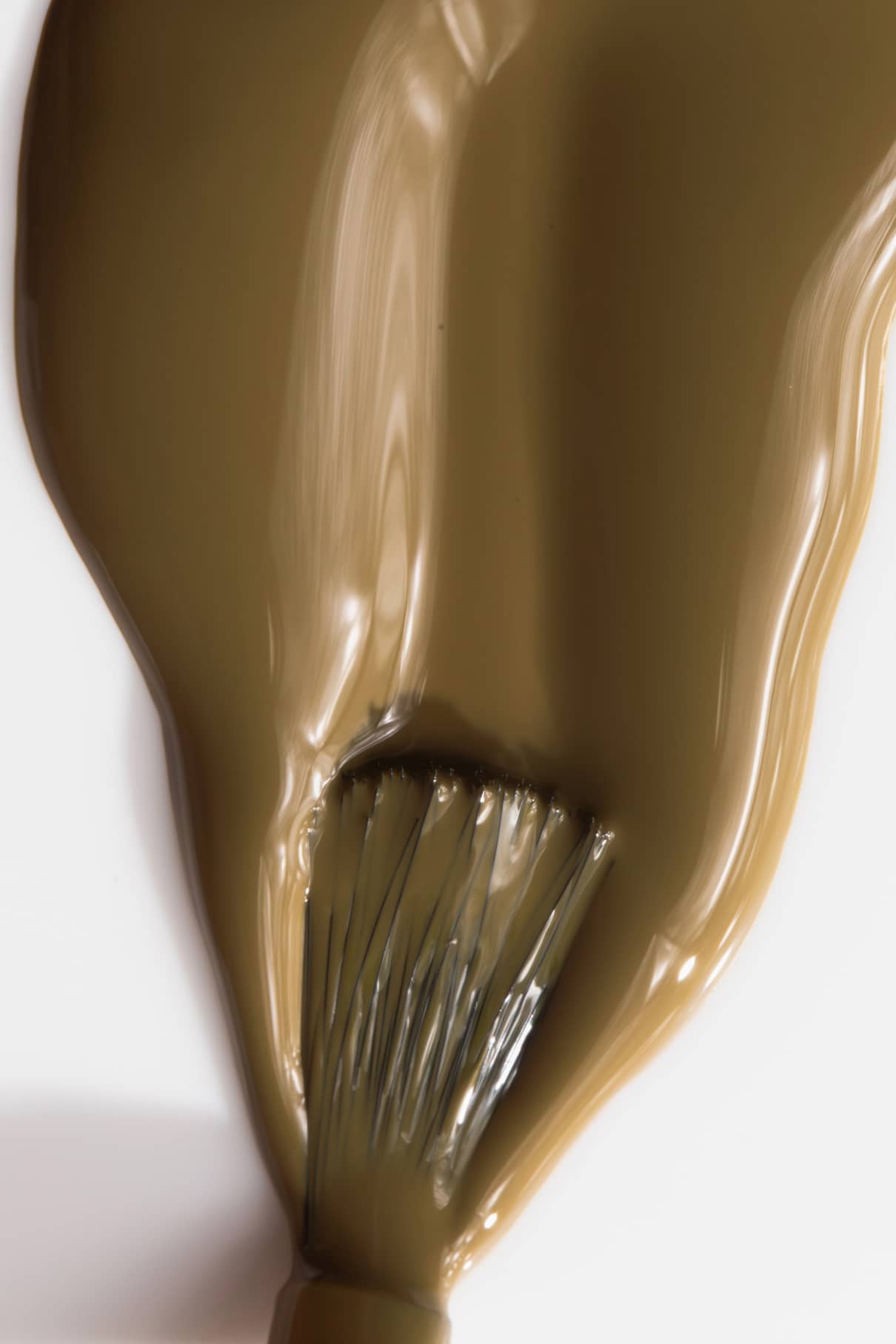 Close-up of a brush with olive green nail polish on a white background
