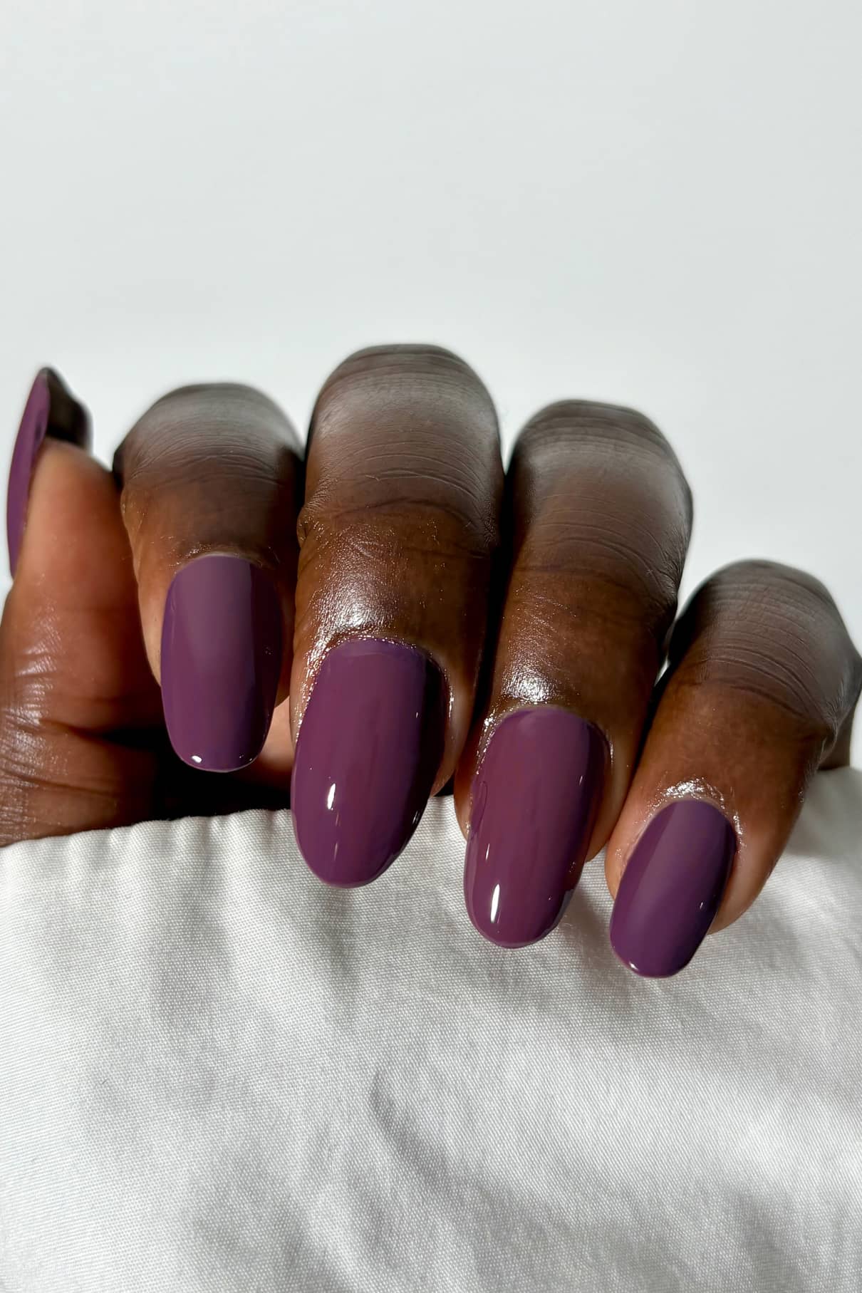 Hand with purple nail polish on a white background