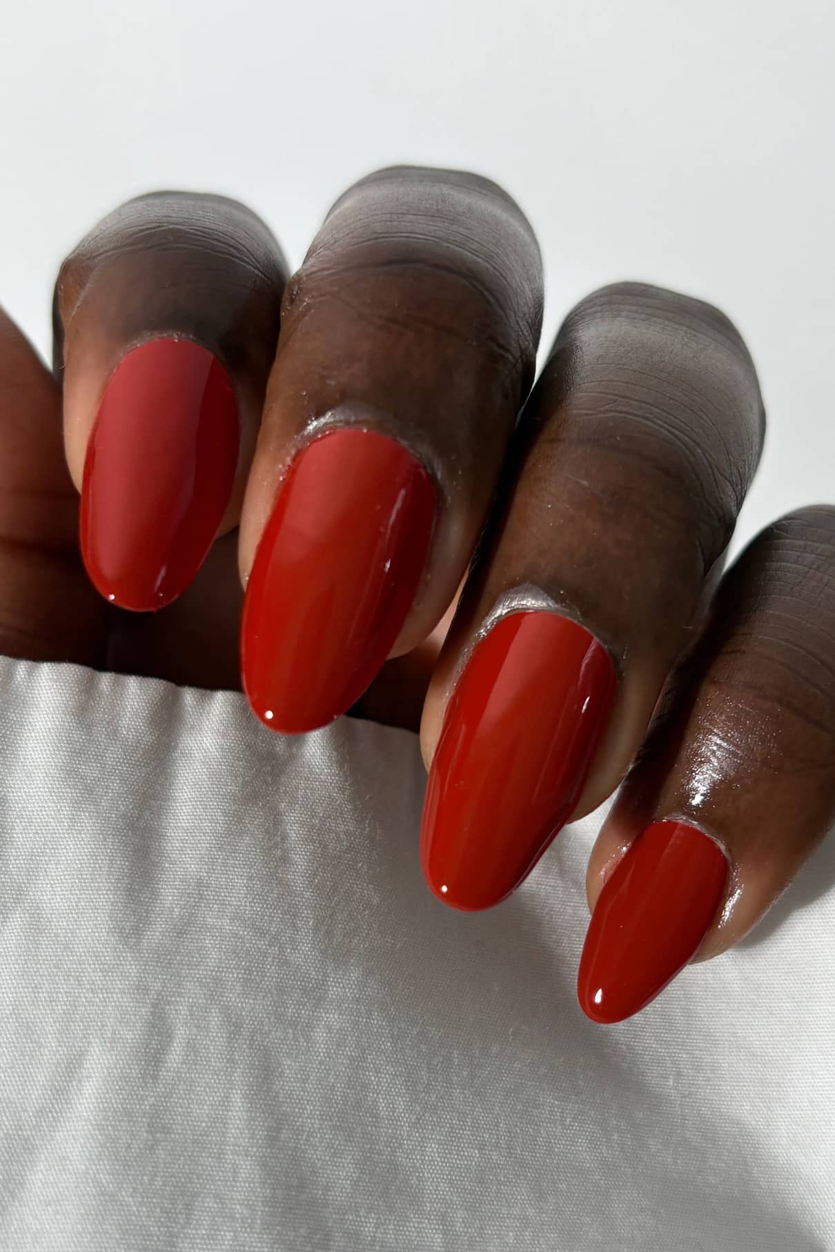 Close-up of a hand with red nail polish on a white background