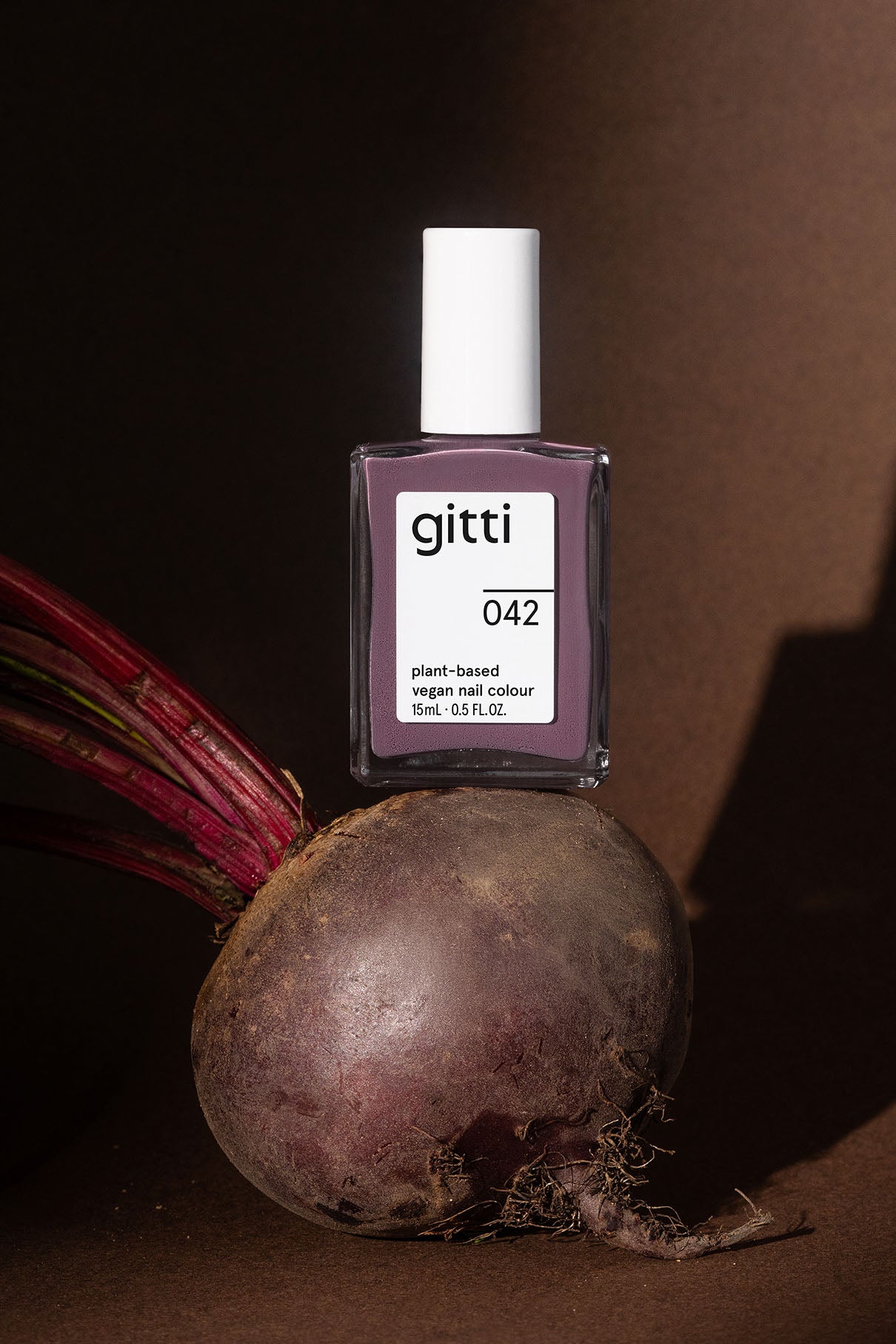 gitti nail polish bottle with a beetroot on a brown background